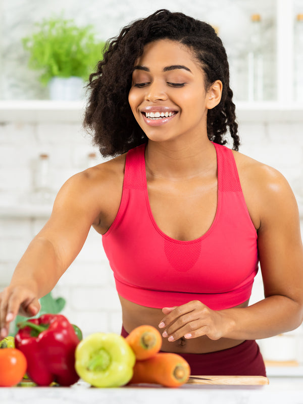 Fit woman putting fresh vegetables on the kitchen table