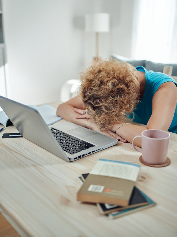 Woman sleeping on her desk, victim of caffeine crash